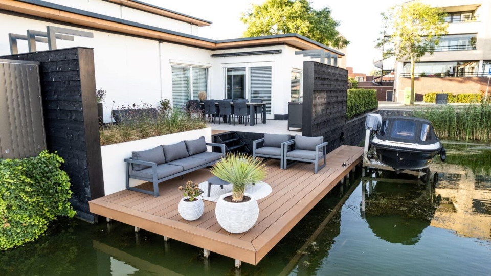 Tuin aan het water in Barendrecht met een modern vlonderterras, niveauverschillen en luxe materialen.