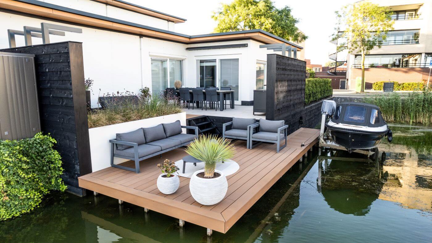 Tuin aan het water in Barendrecht met een modern vlonderterras, niveauverschillen en luxe materialen.