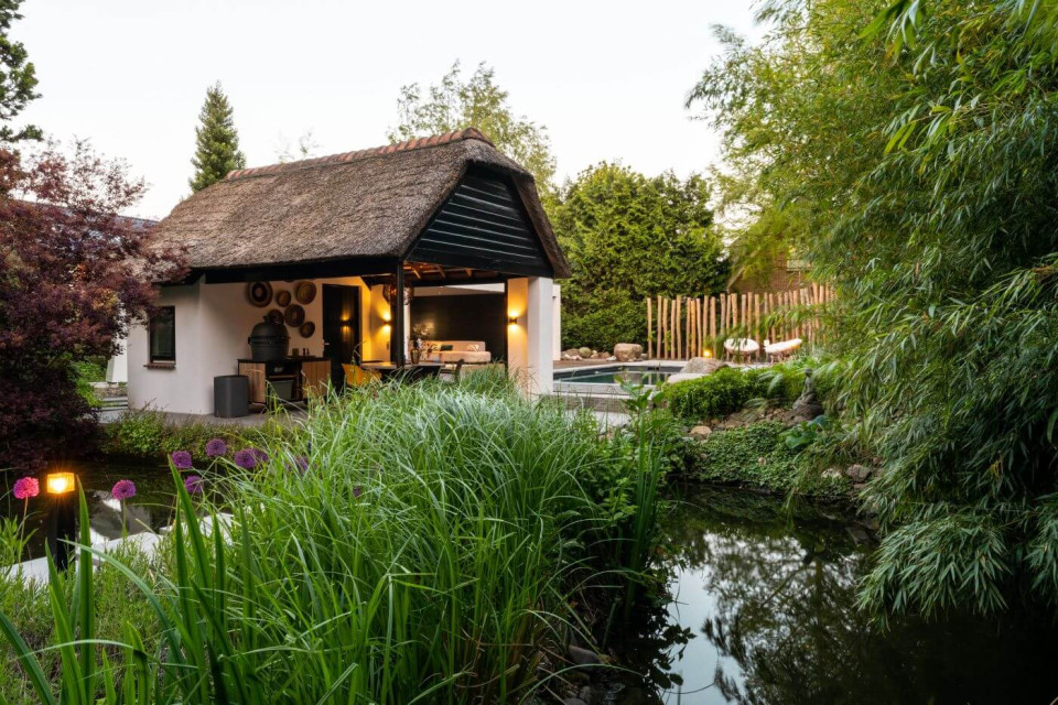 Natuurlijke tuin in Utrecht met een zwembad, poolhouse en een kooikarpervijver