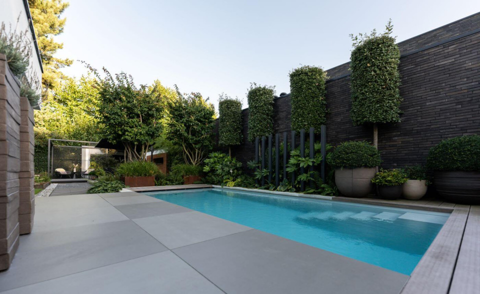 Zwembad met keramische tegels en strakke lijnen in een moderne achtertuin, met een minimalistische en luxe uitstraling.